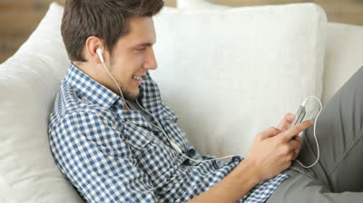 stock-footage-attractive-man-relaxing-on-couch-and-listening-to-music-with-earphones